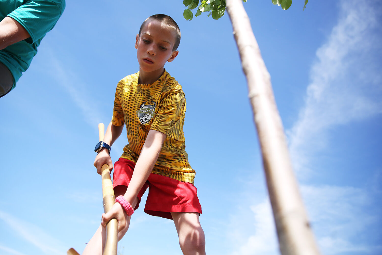 Tyrus Connors drops a shovel full of dirt around the tree roots